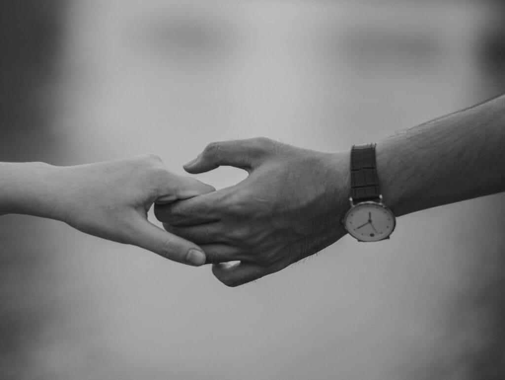 Monochrome image of two hands holding, symbolizing love and connection.