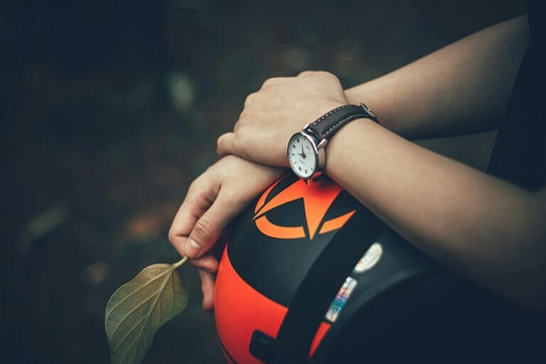 A contemplative moment captured with hands holding a helmet and leaf, wearing a wristwatch.