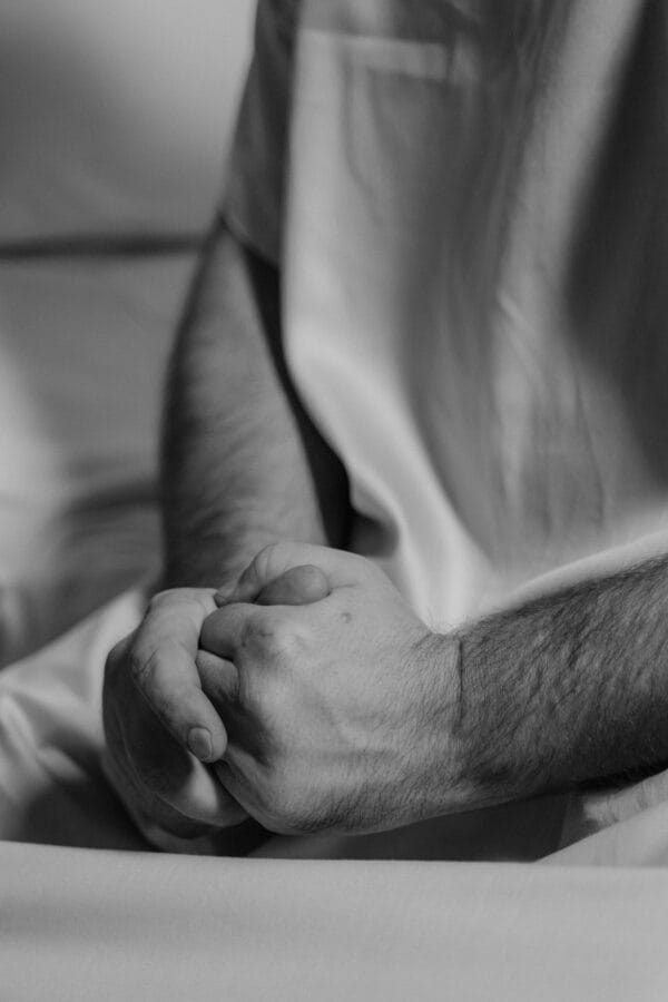 Monochrome image of a person with clasped hands conveying introspection and emotion.