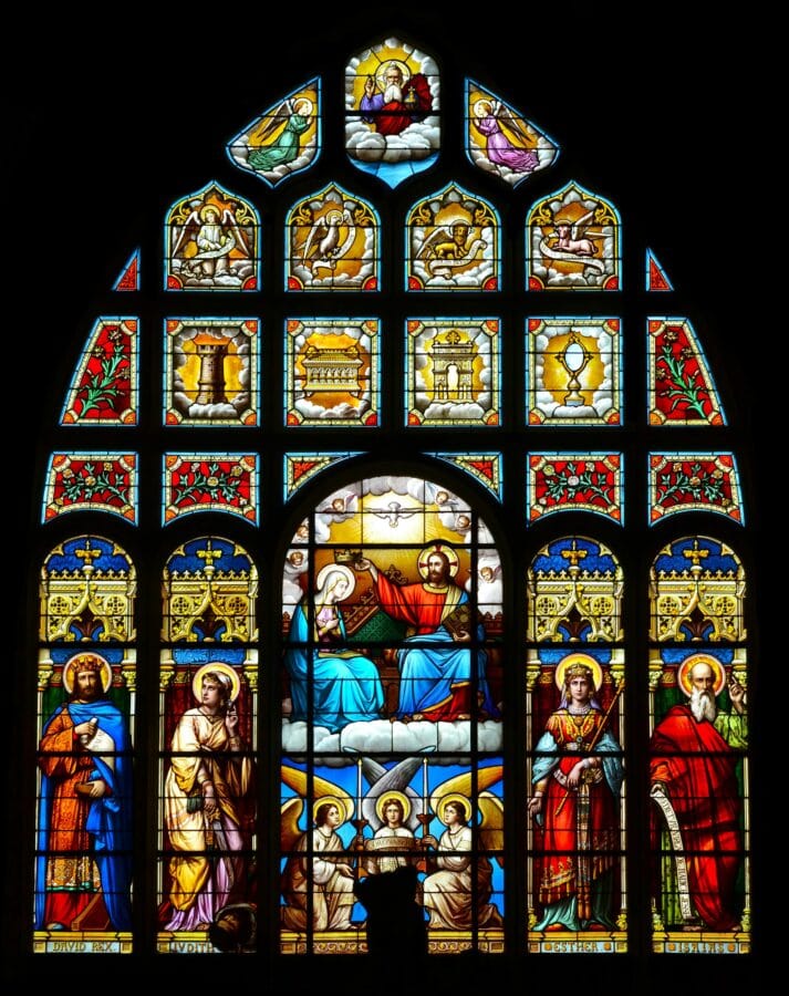 Colorful stained glass window depicting saints and biblical scenes in a cathedral.